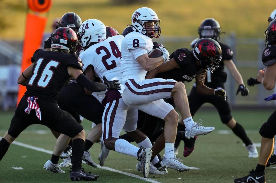 Tates Creek’s Stephen Jones (8) tries to break away from Bulldogs defenders at Paul Laurence Dunbar on Friday night.