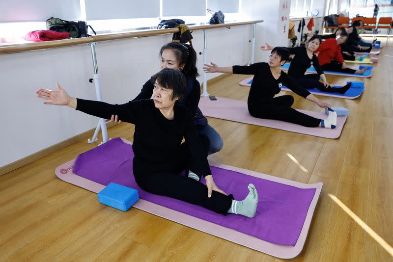 A teacher coaches an elderly person during a yoga class in Beijing
