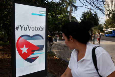 A woman passes by a screen displaying images promoting the vote for "yes" for the constitutional referendum, in Havana, Cuba, February 5, 2019. Picture taken on February 5, 2019. REUTERS/Stringer