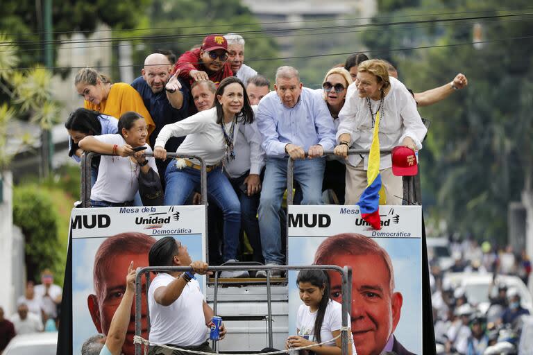 La líder opositora María Corina Machado, centro izquierda, y el candidato presidencial opositor Edmundo González se agachan para evitar cables mientras viajan en la parte superior de un camión durante una protesta contra los resultados oficiales de las elecciones presidenciales que declaran ganador al presidente Nicolás Maduro en Caracas.