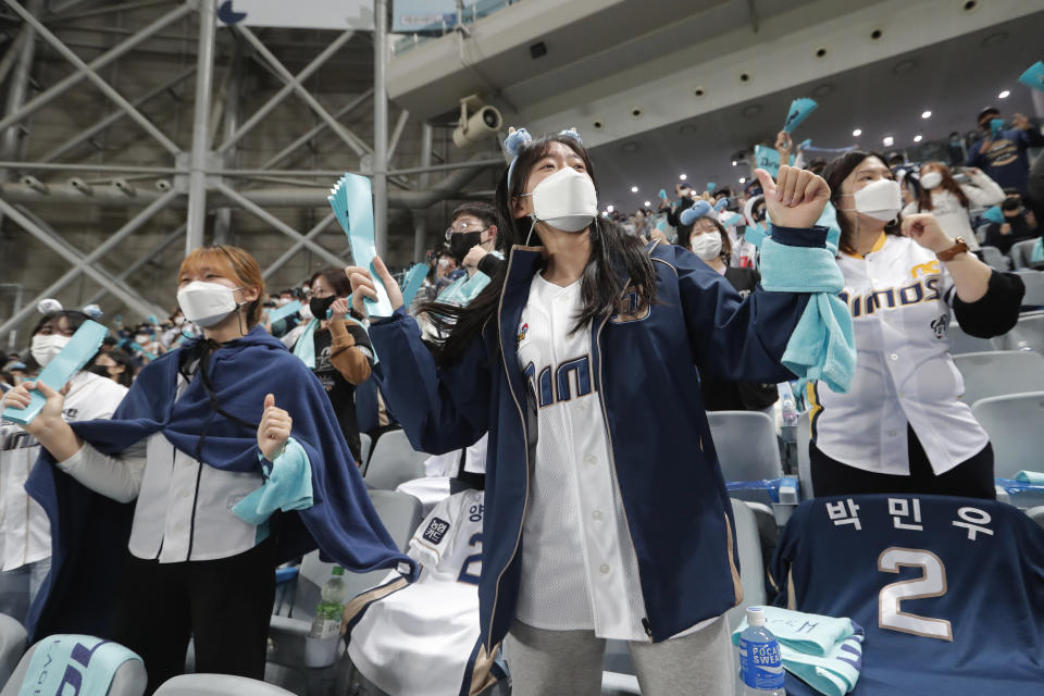 Fans wearing face masks to help protect against the spread of the coronavirus cheer during Game 1 of the Korean Series, the Korea Baseball Organization's championship round, between Doosan Bears and NC Dinos at Gocheok Sky Dome in Seoul, South Korea, Tuesday, Nov. 17, 2020. South Korea says it will tighten social distancing rules in the greater Seoul area and some parts of eastern Gangwon province to try to suppress a coronavirus resurgence there. (AP Photo/Ahn Young-joon)