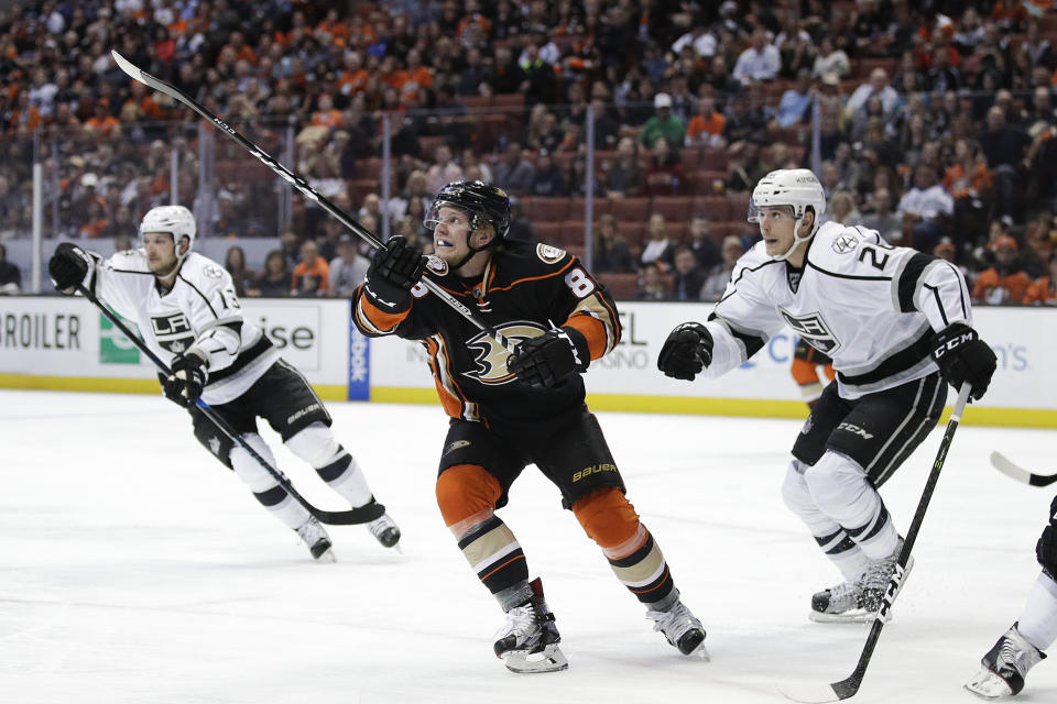 Anaheim Ducks' Ondrej Kase, center, of the Czech Republic, and Los Angeles Kings' Nic Dowd, right, look at the puck in the air during the second period of an NHL hockey game Sunday, April 9, 2017, in Anaheim, Calif. (AP Photo/Jae C. Hong)