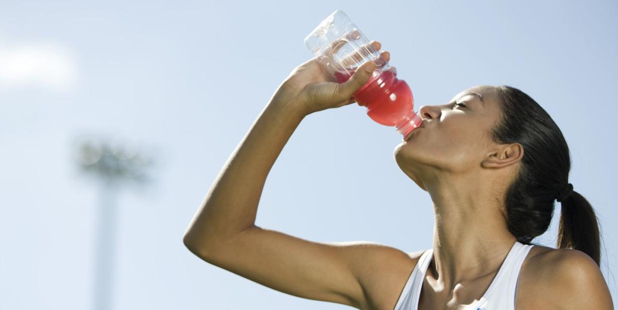 young female athlete drinking sports drink, portrait