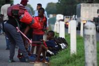 Migrants take a break as they walk along a road in a caravan towards the United States, in Tapachula