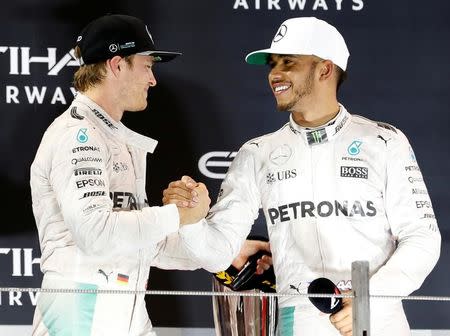 Formula One - F1 - Abu Dhabi Grand Prix - Yas Marina Circuit, Abu Dhabi, United Arab Emirates - 27/11/2016 - Mercedes' Formula One driver Nico Rosberg (L) of Germany shakes hands with Lewis Hamilton of Britain. REUTERS/Ahmed Jadallah