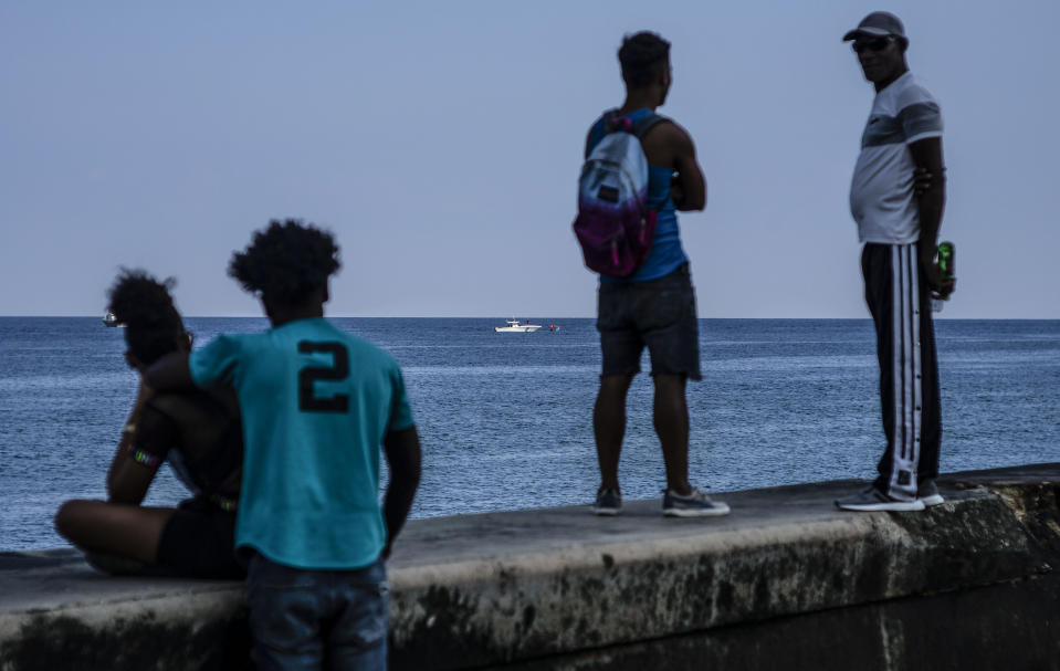 People watch the Cuban Coast Guard capture a makeshift boat, from the Malecon seawall in Havana, Cuba, Monday, Dec. 12, 2022. (AP Photo/Ramon Espinosa)