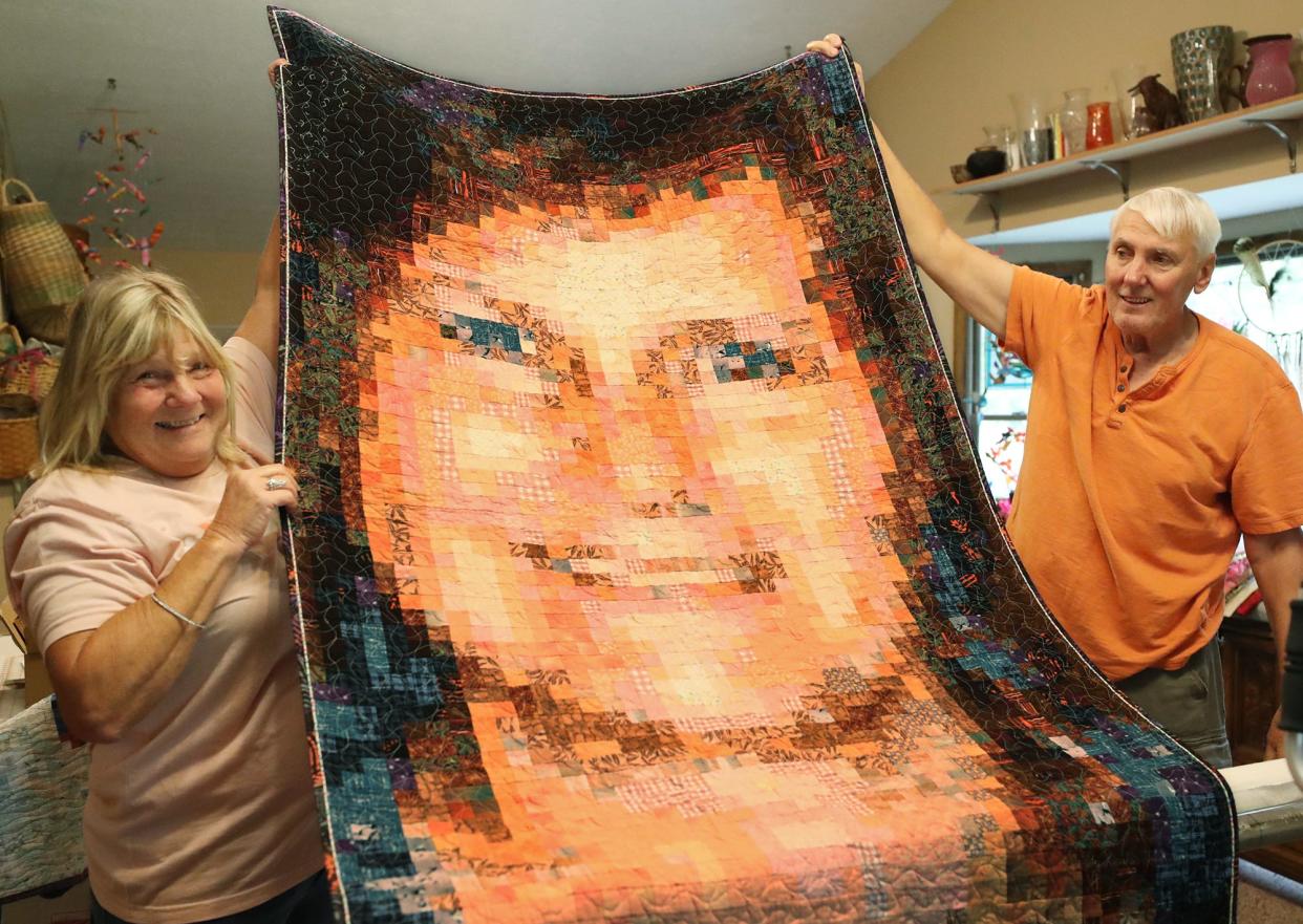 Dianne Shaffer, Wendy Lewis' sister and Walt Grandell, Wendy's husband, hold a pixel quilt self portrait of Wendy in her quilting room at his home in Green.