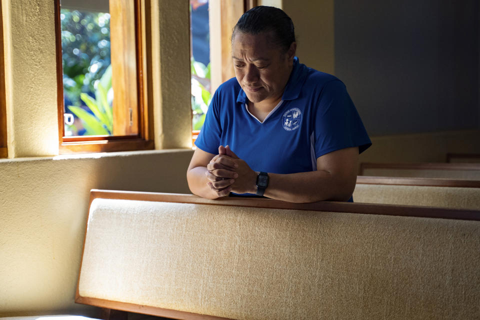 Sacred Hearts School Principal Tonata Lolesio prays after a school day at their temporary location at Sacred Hearts Mission Church on Tuesday, Oct. 3, 2023, in Lahaina, Hawaii. Sacred Hearts School, a Catholic school was founded in 1862. Most of the school burned down, but its leaders quickly got classes up and running at Sacred Hearts Mission Church 10 miles (16 kilometers) away. (AP Photo/Mengshin Lin)