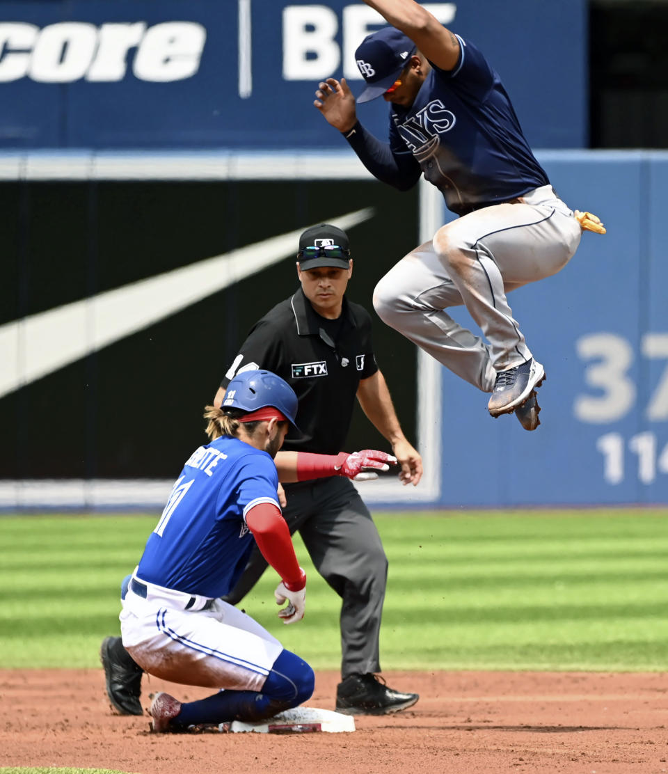Toronto Blue Jays' shortstop Bo Bichette, left, slides safely into second base for a double under a jumping Tampa Bay Rays' Wander Franco during the first inning of a baseball game, Saturday, July 2, 2022 in Toronto. (Jon Blacker/The Canadian Press via AP)