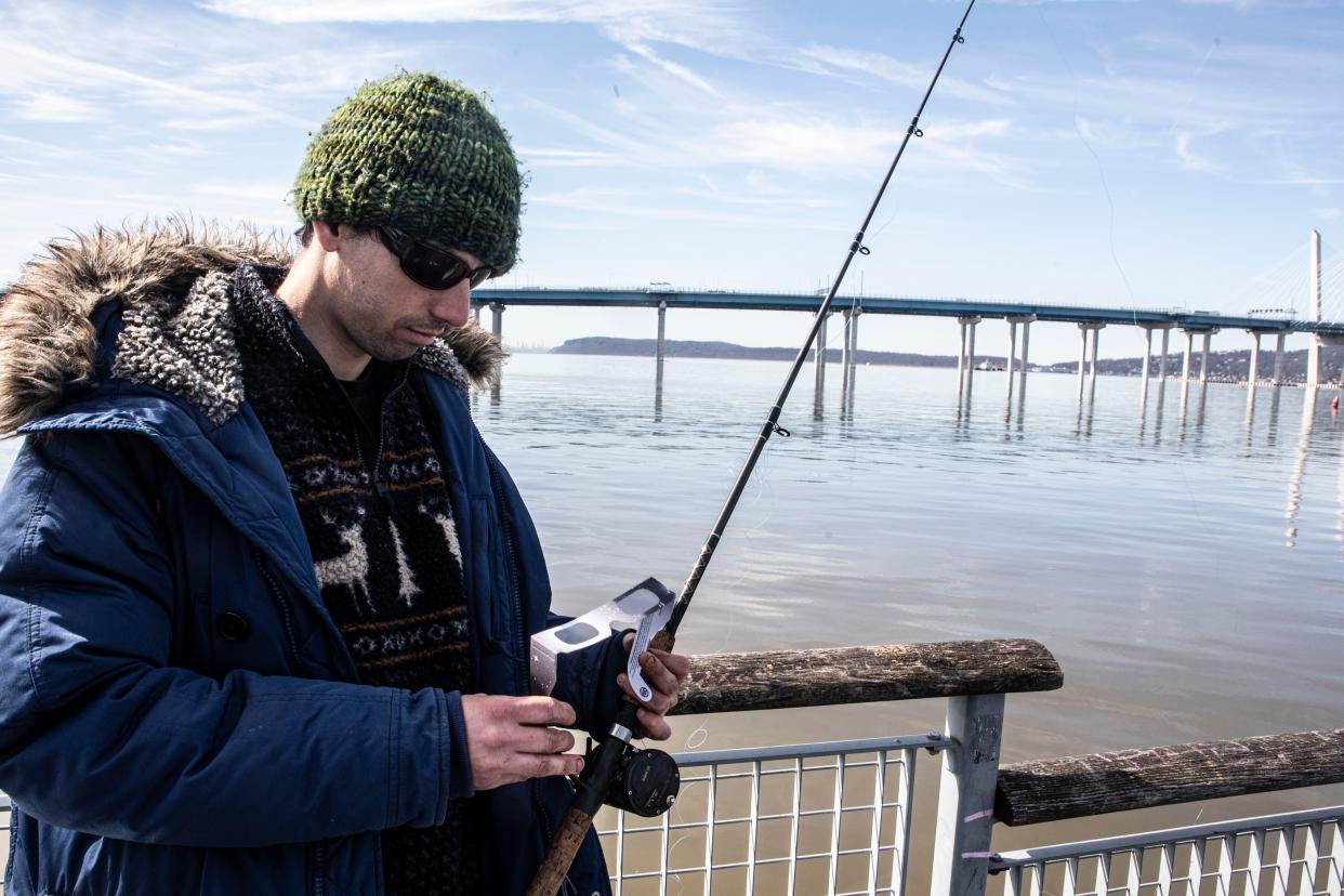 Alex Goldsmith, 28, of Cold Spring has his eclipse glasses ready to go as he fishes in the Hudson River in Tarrytown April 8, 2024. Alex and a friend were planning on watching the eclipse while spending the day fishing for striped bass.
