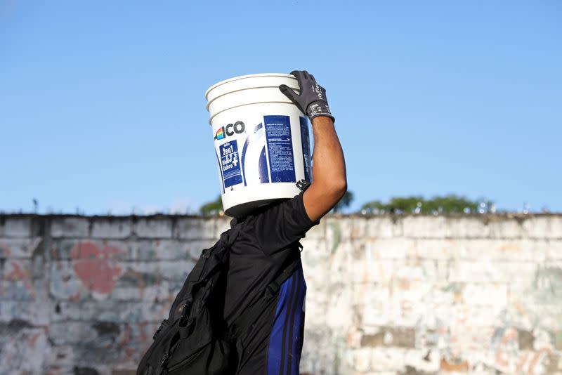 Juan Meza carries a plastic bucket filled with chickens as he walks in the streets of San Joaquin