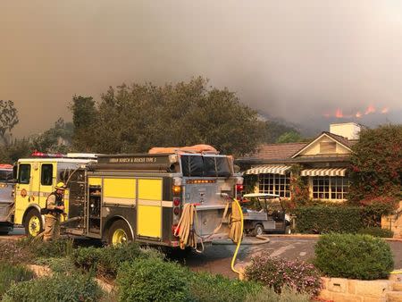 Firefighters provide structure protection at the historic San Ysidro Ranch as flames from the Thomas Fire, now the third-largest on record, rage in the distance in Montecito, California, U.S., December 16, 2017. Courtesy Mike Eliason/Santa Barbara County Fire Department/Handout via REUTERS