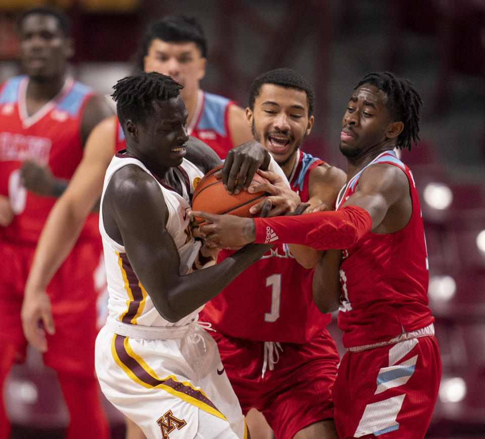 Minnesota guard Both Gach, left, wrestles for the ball with Loyola Marymount guard Dameane Douglas (1) and Jalin Anderson, right, in the first half of an NCAA college basketball game Monday, Nov. 30, 2020, in Minneapolis. (Jeff Wheeler/Star Tribune via AP)