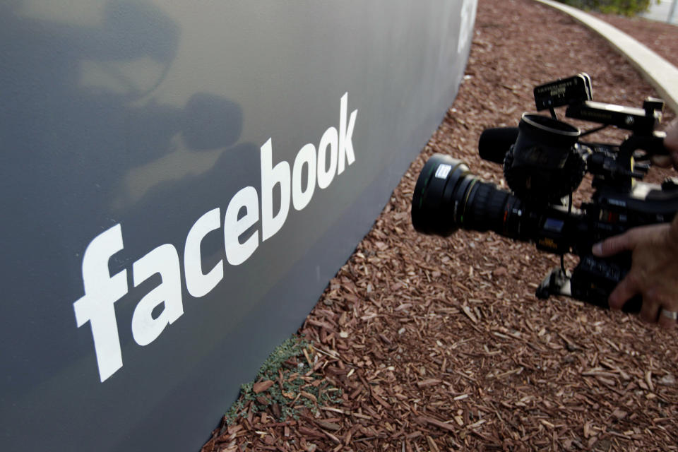 FILE- In this May 18, 2012, file photo a television photographer shoots the sign outside of Facebook headquarters in Menlo Park, Calif. Facebook says it has removed 783 Iran-linked pages, accounts and groups from its service for what it calls “coordinated inauthentic behavior,” that is, misrepresenting who is running the accounts with the intent of disrupting politics and elections. (AP Photo/Paul Sakuma, File)