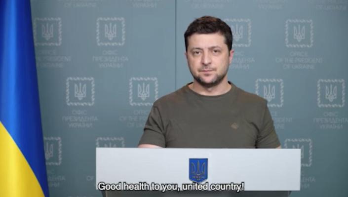 Volodymyr Zelensky speaks at a podium with Ukraine&#39;s flag behind him