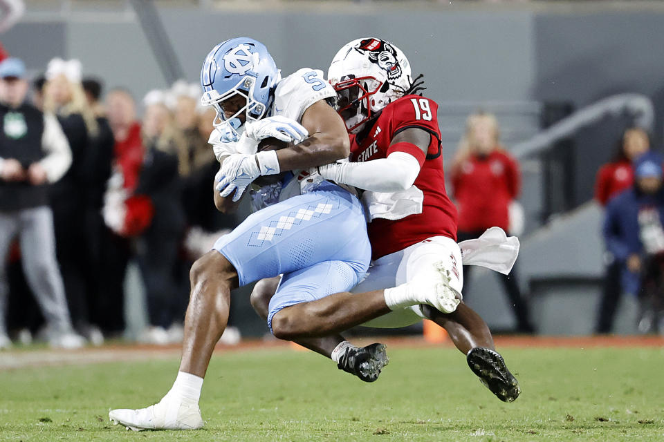 North Carolina wide receiver J.J. Jones (5) is tackled by North Carolina State safety Bishop Fitzgerald (19) after a long reception during the first half of an NCAA college football game in Raleigh, N.C., Saturday, Nov. 25, 2023. (AP Photo/Karl B DeBlaker)