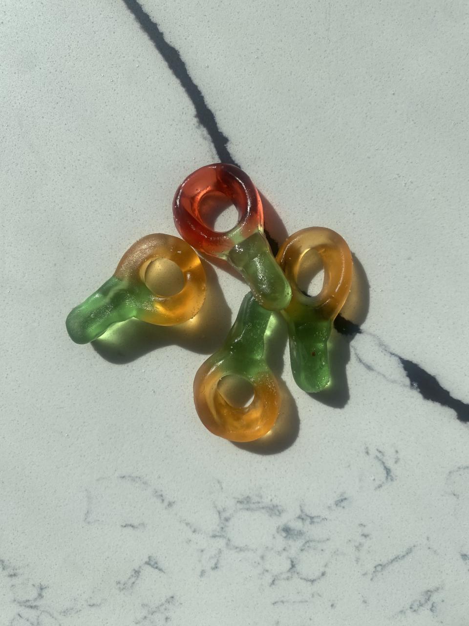 Four gummy candy rings with different flavors arranged on a marble surface