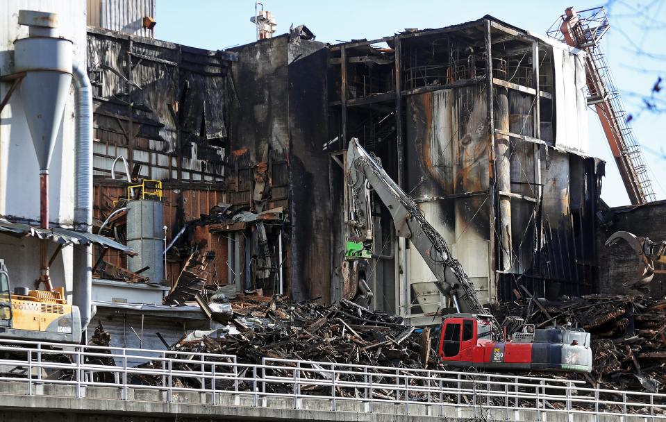 Heavy machinery is used to remove rubble on Monday from the scene where a large structure fire last week destroyed a part of the Star of the West mill complex in Kent.