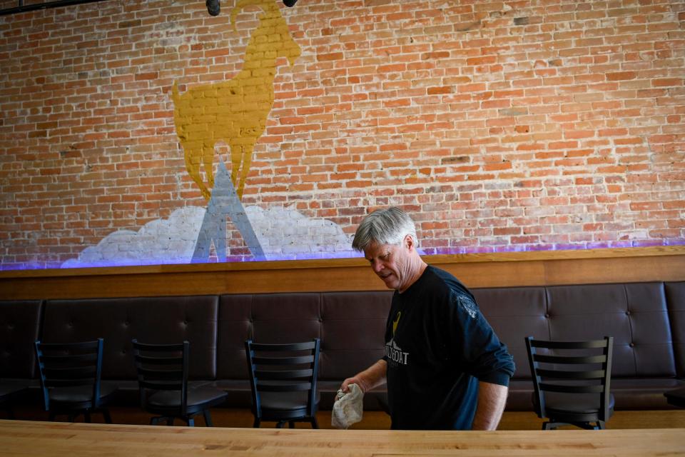 Gilded Goat Brewing Co. founder John Hoxmeier cleans tables inside the brewery's new Old Town Fort Collins location on Friday.