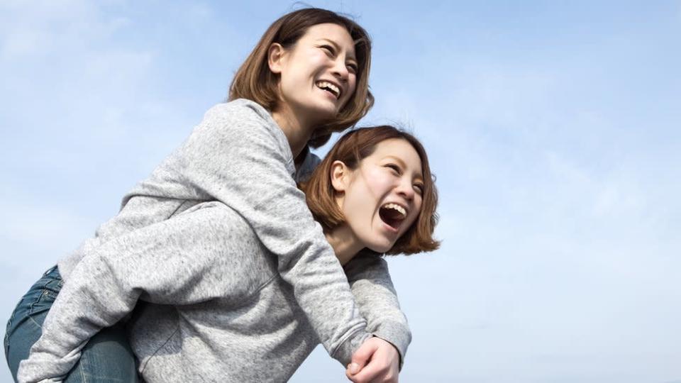 Una joven salta sobre su hermana gemela y ambas ríen