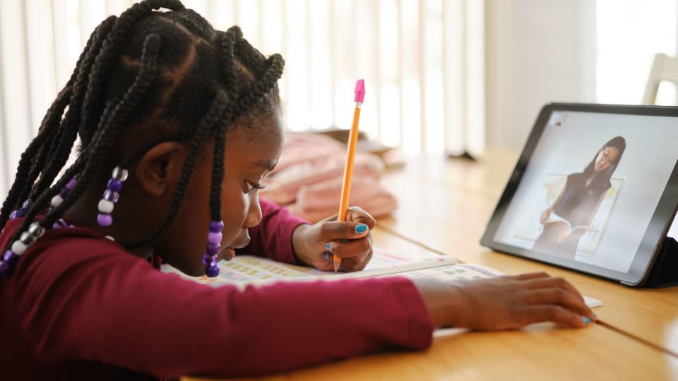 An elementary aged school student in a home doing remote learning.