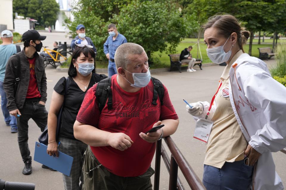 A man speaks to a medical worker as pother people wearing face masks to protect against coronavirus stand in line to get a coronavirus vaccine at a vaccination point in Gorky Park in Moscow, Russia, Wednesday, June 30, 2021. Russia was among the first in the world to announce and deploy a coronavirus vaccine last year, but so far only about 23 million, just over 15% of the population have received at least one vaccine shot. Hampered by widespread vaccine hesitancy and limited production capacity, Russia's vaccination rates have picked up in recent weeks, after authorities in many regions made shots mandatory for employees in certain sectors. (AP Photo/Alexander Zemlianichenko)