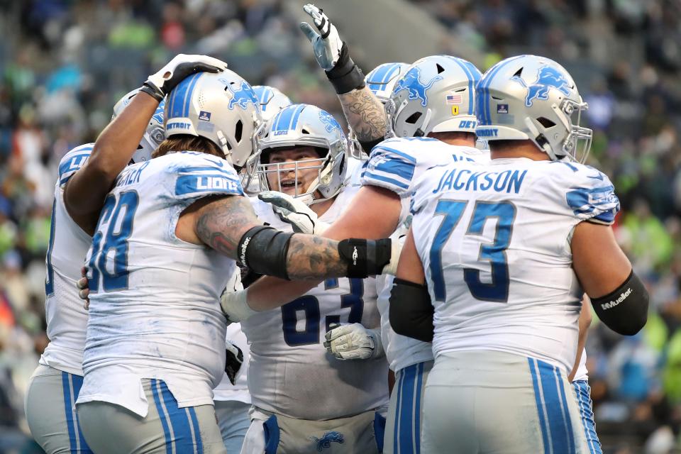 Lions offensive lineman Taylor Decker, left, celebrates his touchdown catch with teammates during the third quarter of the Lions' 51-29 loss on Sunday, Jan. 2, 2022, in Seattle.