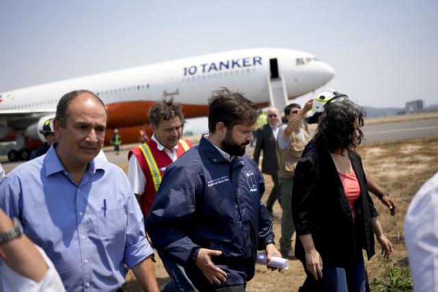 El presidente chileno Gabriel Boric camina cerca del avión 10 Tanker, que llevará agua para rociar sobre los incendios forestales, mientras se llena de agua en el aeropuerto de Talcahuano, Chile, el lunes 6 de febrero de 2023.