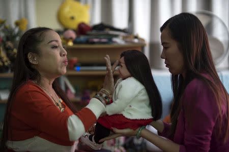 Mananya Boonmee (L), 49, performs a ritual on a "child angel" doll and her owner Manita Chuenarom (R), 33, at her house in Nonthaburi, Thailand, January 26, 2016. REUTERS/Athit Perawongmetha