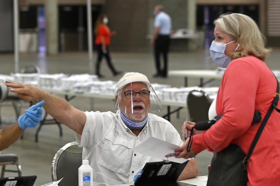 Poll workers instruct a voter on where to go to fill out their ballot during the Kentucky primary at the Kentucky Exposition Center in Louisville, Ky., Tuesday, June 23, 2020. In an attempt to prevent the spread of the coronavirus, neighborhood precincts were closed and voters that didn't cast mail in ballots were directed to one central polling location. (AP Photo/Timothy D. Easley)