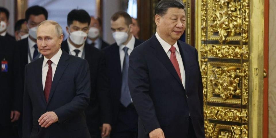 Russian President Vladimir Putin with China's leader, Xi Jinping, in front of a golden door.