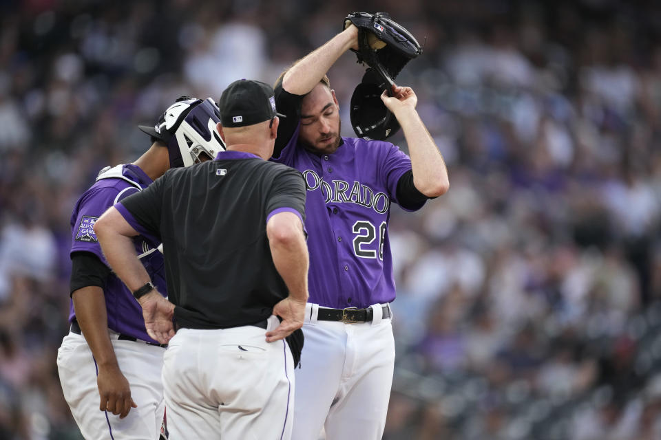 Colorado Rockies pitching coach Steve Foster, front, confers with catcher Elias Diaz, left, and starting pitcher Austin Gomber during the first inning of the team's baseball game against the Milwaukee Brewers on Saturday, June 19, 2021, in Denver. (AP Photo/David Zalubowski)