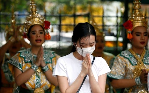 A worshipper wearing protective mask offers prayers in Bangkok after Thai health official confirmed its found two cases of coronavirus - Credit: RUNGROJ YONGRIT/EPA-EFE/REX