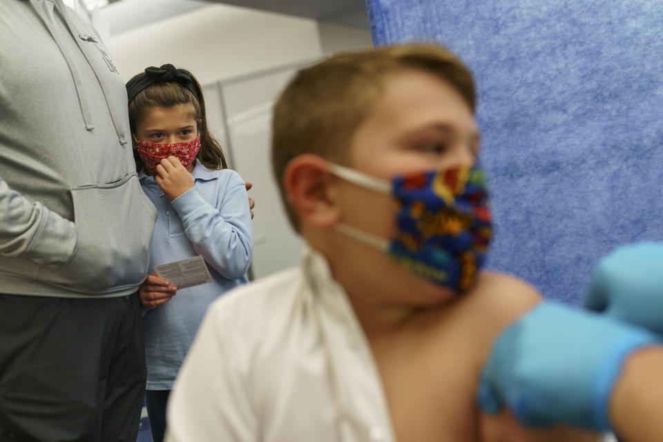 FILE - Michael Farias, left, holds his daughter, McKenzie, 8, as she watches her brother, Mikey, 10, receive the Pfizer COVID-19 vaccine for children ages 5 to 11 at a state-run site in Cranston, R.I., Nov. 4, 2021. First shots are averaging about 300,000 per day. (AP Photo/David Goldman, File)