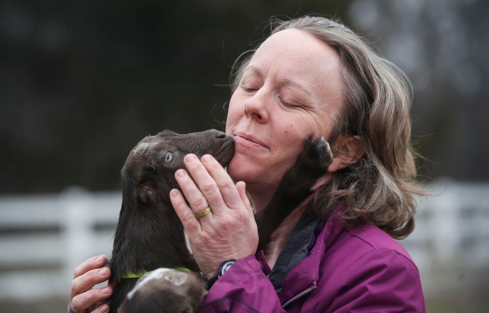 Beth Boesche-Taylor gets a friendly nuzzle from one of the new baby goats at their Sirocco Ridge Farm in Henryville, Ind. March 16, 2023.
