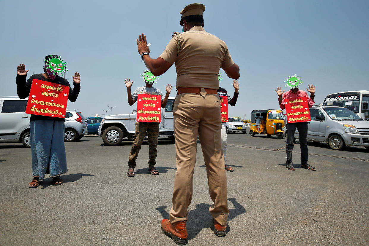 People wear masks depicting coronavirus and placards which read: "Don't come out, don't go near to corona" provided by police as part of a punishment for breaking a lockdown imposed to slow the spreading of coronavirus disease (COVID-19) in Chennai, India, April 1, 2020. REUTERS/P. Ravikumar