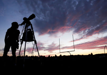 A woman looks through a telescope on the football field at Madras High School the evening before a solar eclipse in Madras, Oregon, U.S., August 20, 2017. Picture taken August 20, 2017. REUTERS/Jason Redmond