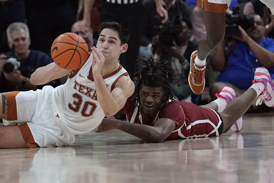 Texas forward Brock Cunningham (30) and Oklahoma guard Otega Oweh, right, scramble for the ball during overtime of an NCAA college basketball game in Austin, Texas, Saturday, Feb. 18, 2023. (AP Photo/Eric Gay)