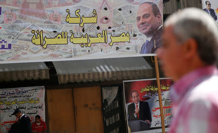 People are seen in front of an exchange bureau, with an advertisement showing images of the U.S. dollar and other foreign currency and a poster supporting Egypt's President Abdel Fattah al-Sisi for the upcoming presidential election in Cairo, Egypt March 14, 2018. REUTERS/Amr Abdallah Dalsh