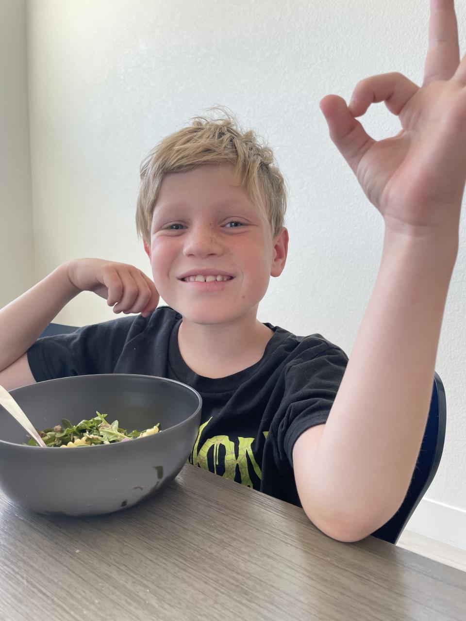 The author's son eating lunch and giving an A-OK gesture