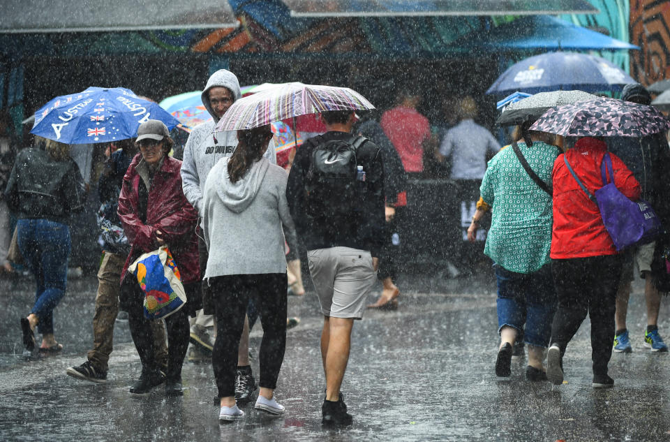 Spectators are seen as rain falls during the first round matches during day one of the Australian Open tennis tournament in Melbourne.