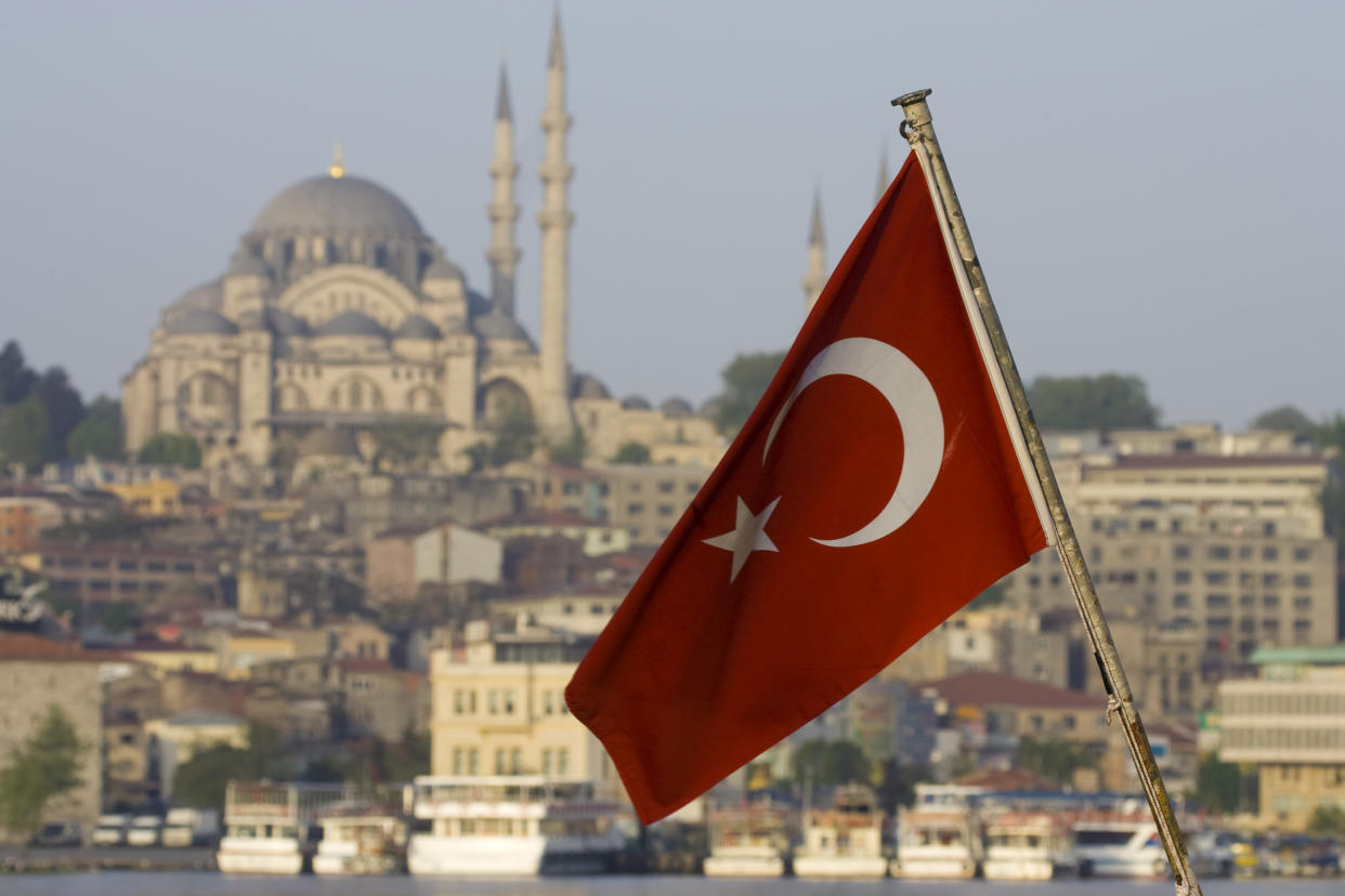 Turkish Flag on back of boat on the Bosphorus and Mosque on hillside just above