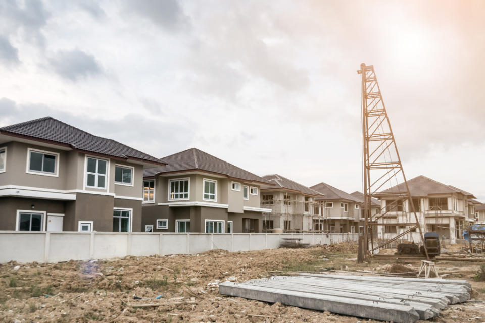 house building at construction site with pile driver and concret