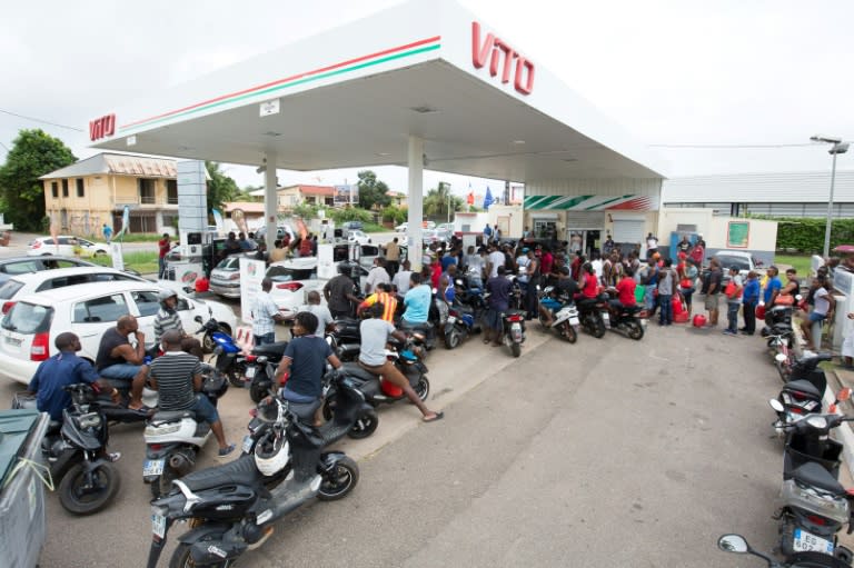 People queue with vehicles and jerrycans after a tank truck was able to resupply an out-of-fuel petrol station in Cayenne, French Guiana's capital