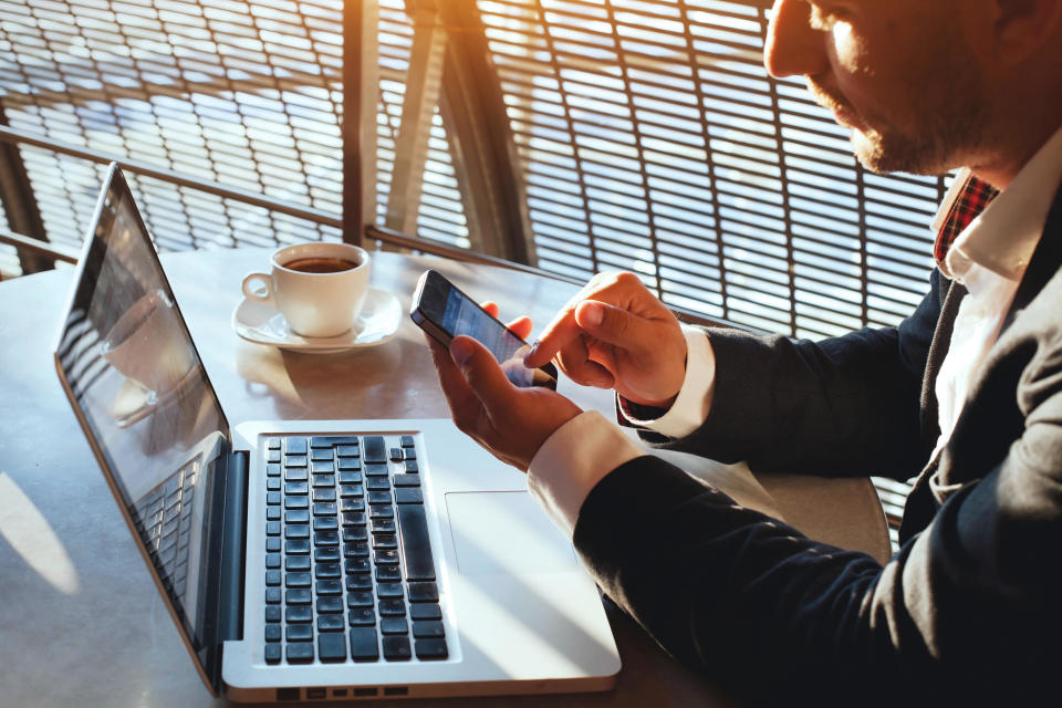 Business man using internet on smart phone and laptop (Alamy/PA)