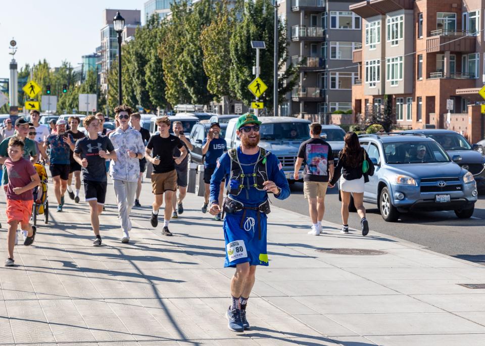 Greg Nance jogs with a group toward a group of supporters waiting for him on the Seattle waterfront in July 2022.