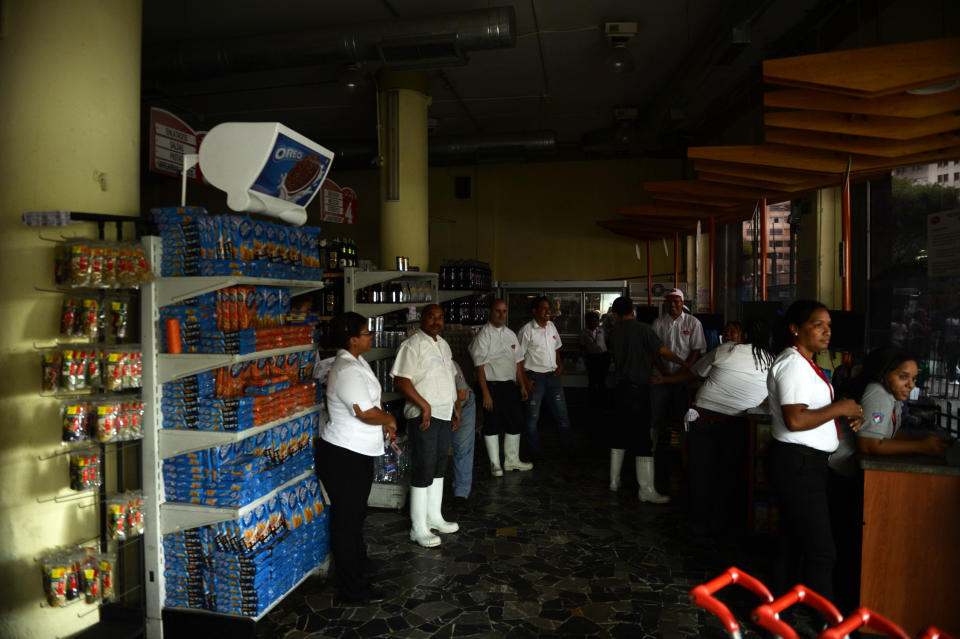 Empleados de un supermercado esperan tras cerrar el local por el apagón este martes en Caracas