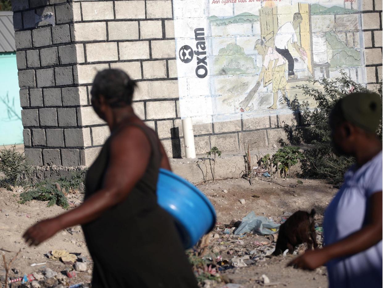People walk past an Oxfam sign in Corail, a camp for people displaced after 2010 earthquake, on the outskirts of Port-au-Prince, Haiti: Reuters