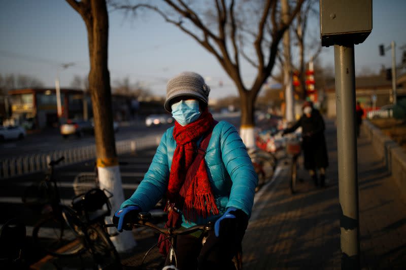 A woman wearing a face mask rides a bicycle as the country is hit by an outbreak of the new coronavirus, in Beijing