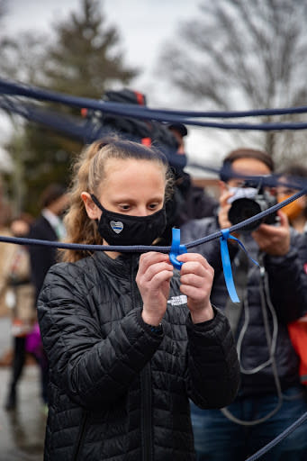 March 1: Hailey Van Zeyl ties a ribbon for her father, Robert, who died from the virus, at a COVID-19 memorial in Hauppauge, New York. (Getty Images)